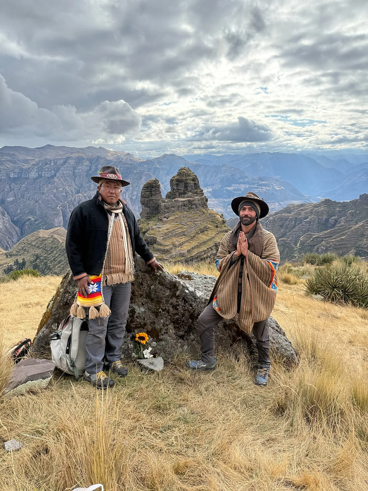 Izzy with hands together beside an elder at stone ruins