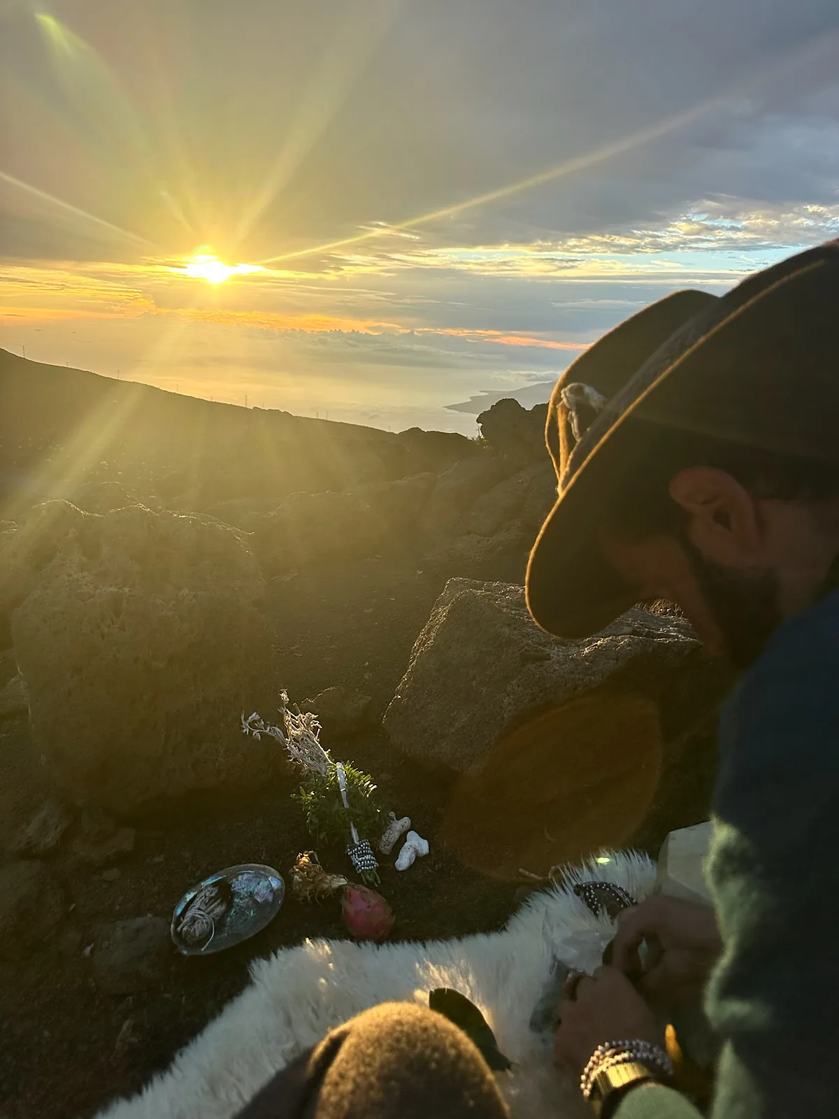 Izzy at first light, hat down and head bowed over a rock, quiet with what is in front of him